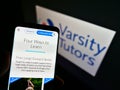 Person holding mobile phone with website of US learning platform Varsity Tutors on screen in front of logo.