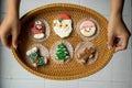 Person holding Oval Rattan Tray with Christmas Gingerbread Cookies in different Forms with both Hands