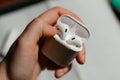 A person holding a pair of wireless earbuds in an open charging case, highlighting everyday tech use and portability Royalty Free Stock Photo