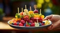 A person holding a plate of fruit skewers