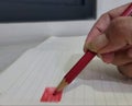 A person holding a Red color pencil coloring on a paper Royalty Free Stock Photo