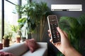 A person holding a remote control in their hand to control air conditioner Royalty Free Stock Photo