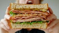 A person holding a sandwich with ham, lettuce and cheese, AI Royalty Free Stock Photo