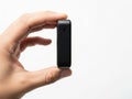A person holding a sleek black electronic device in their hand against a plain background Royalty Free Stock Photo