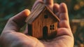 Person Holding Small Wooden House, Symbolizing Homeownership and Stability Royalty Free Stock Photo
