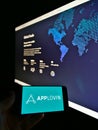 Person holding smartphone with business logo of American mobile technology platform AppLovin on screen in front of website.
