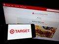 Person holding smartphone with business logo of American retail company Target Corporation on screen in front of website.