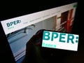 Person holding smartphone with business logo of Italian bank BPER Banca S.p.A. on screen in front of company website.