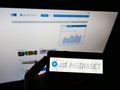 Person holding smartphone with business logo of Italian mass media company Mediaset S.p.A. on screen in front of website.