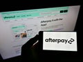Person holding smartphone with logo of Australian fintech company Afterpay Limited on screen in front of business web page.