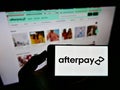 Person holding smartphone with logo of Australian fintech company Afterpay Limited on screen in front of website. Royalty Free Stock Photo