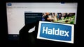 Person holding smartphone with logo of automotive company Haldex Europe SAS on screen in front of website. Royalty Free Stock Photo