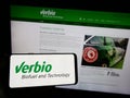 Person holding smartphone with logo of biofuel company Verbio Vereinigte Bioenergie AG on screen in front of website. Royalty Free Stock Photo