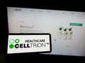 Person holding smartphone with logo of biopharmaceutical company Celltrion Inc. on screen in front of website.