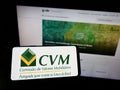 Person holding smartphone with logo of Brazilian Comissao de Valores Mobiliarios (CVM) on screen in front of website. Royalty Free Stock Photo