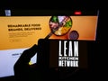 Person holding smartphone with logo of British company Lean Kitchen Network Limited (LKN) on screen in front of website. Royalty Free Stock Photo