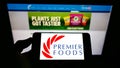 Person holding smartphone with logo of British food manufacturer Premier Foods plc on screen in front of website.
