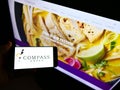 Person holding smartphone with logo of British foodservice company Compass Group plc on screen in front of website. Royalty Free Stock Photo