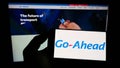 Person holding smartphone with logo of British transport company The Go-Ahead Group plc on screen in front of website.