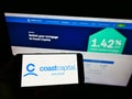 Person holding smartphone with logo of Canadian Coast Capital Savings Federal Credit Union on screen in front of website.