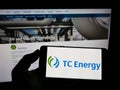 Person holding smartphone with logo of Canadian company TC Energy Corporation on screen in front of website.