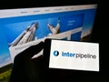 Person holding smartphone with logo of Canadian oil infrastructure company Inter Pipeline Ltd. on screen in front of website.