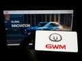 Person holding smartphone with logo of car manufacturer Great Wall Motors Co. Ltd. (GWM) on screen in front of website.