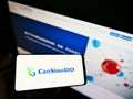 Person holding smartphone with logo of Chinese company CanSino Biologics Inc. (CanSinoBIO) on screen with website.