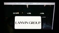 Person holding smartphone with logo of Chinese fashion company Lanvin Group on screen in front of website.