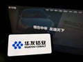 Person holding smartphone with logo of Chinese mining company Huayou Cobalt Co. Ltd. on screen in front of website.