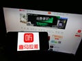 Person holding smartphone with logo of Chinese online radio platform Ximalaya on screen in front of website.