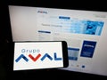 Person holding smartphone with logo of Colombian Grupo Aval Acciones y Valores S.A. on screen in front of website. Royalty Free Stock Photo