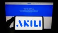 Person holding smartphone with logo of company Akili Interactive Labs Inc. on screen with website.