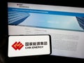 Person holding smartphone with logo of company China Energy Investment Corporation on screen in front of website.