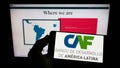 Person holding smartphone with logo of Corporacion Andina de Fomento (CAF) on screen in front of website. Royalty Free Stock Photo