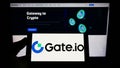 Person holding smartphone with logo of crypto exchange company Gate Global Corp. on screen in front of website.