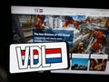 Person holding smartphone with logo of Dutch manufacturing company VDL Groep B.V. on screen in front of website.