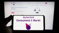 Person holding smartphone with logo of Dutch regulator Autoriteit Consument en Markt (ACM) on screen with website. Royalty Free Stock Photo