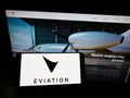 Person holding smartphone with logo of electric aircraft company Eviation Aircraft Ltd. on screen in front of website.