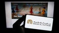 Person holding smartphone with logo of Emirati company Majid Al Futtaim Group on screen in front of website.