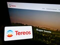 Person holding smartphone with logo of French agriculture company Tereos S.A. on screen in front of website.