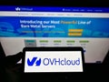 Person holding smartphone with logo of French cloud computing company OVH Groupe SAS on screen in front of website.