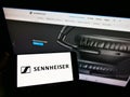 Person holding smartphone with logo of German audio company Sennheiser electronic GmbH Co. KG on screen in front of website.