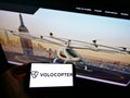 Person holding smartphone with logo of German helicopter manufacturer Volocopter GmbH on screen in front of website.