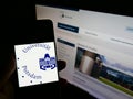 Person holding smartphone with logo of German university UniversitÃÂ¤t Potsdam on screen in front of website.