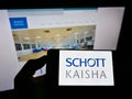 Person holding smartphone with logo of Indian packaging company Schott Kaisha Pvt. Ltd. on screen in front of website. Royalty Free Stock Photo