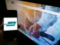 Person holding smartphone with logo of Instituto de Resseguros do Brasil (IRB Brasil RE) on screen in front of website.