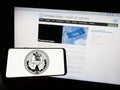 Person holding smartphone with logo of the International Court of Justice (ICJ) on screen in front of website.