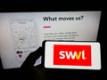 Person holding smartphone with logo of mass transit company SWVL Technologies Inc. on screen in front of website.