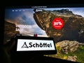 Person holding smartphone with logo of outdoor clothing company SchÃÂ¶ffel on screen in front of online shop website.